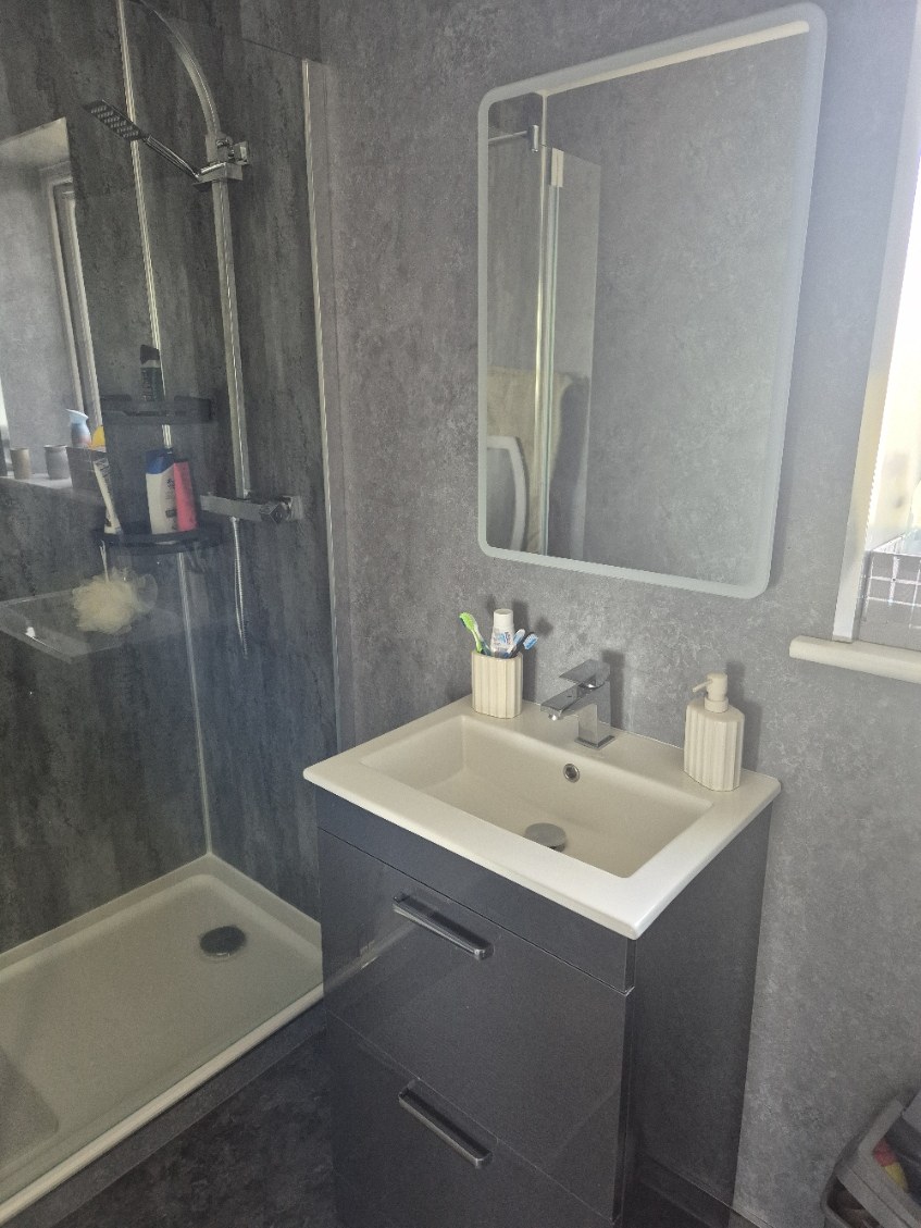 Grey shower room with vanity and illuminated mirror