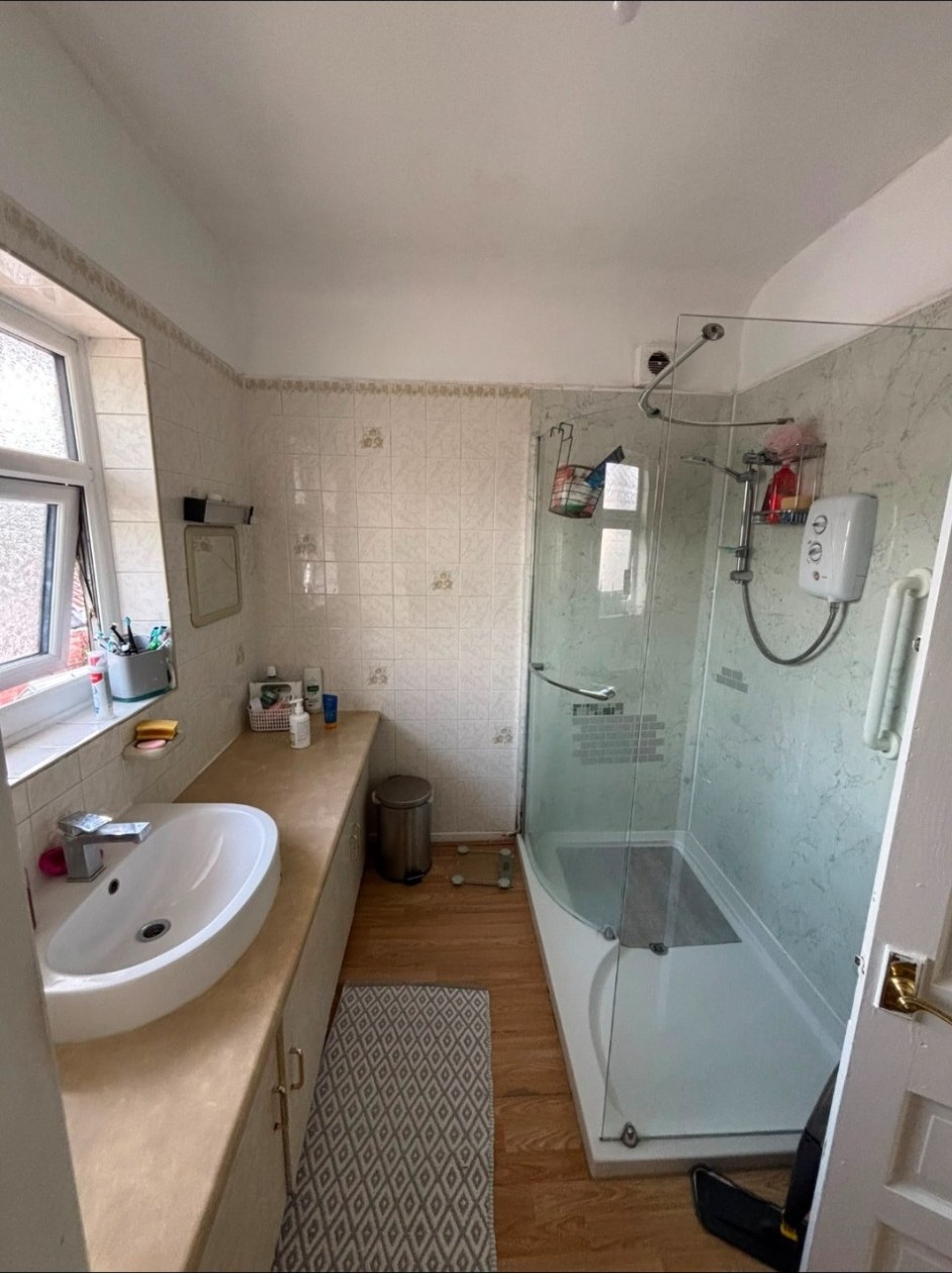Wider view of an existing bathroom showing bath, shower screen, basin and original finishes