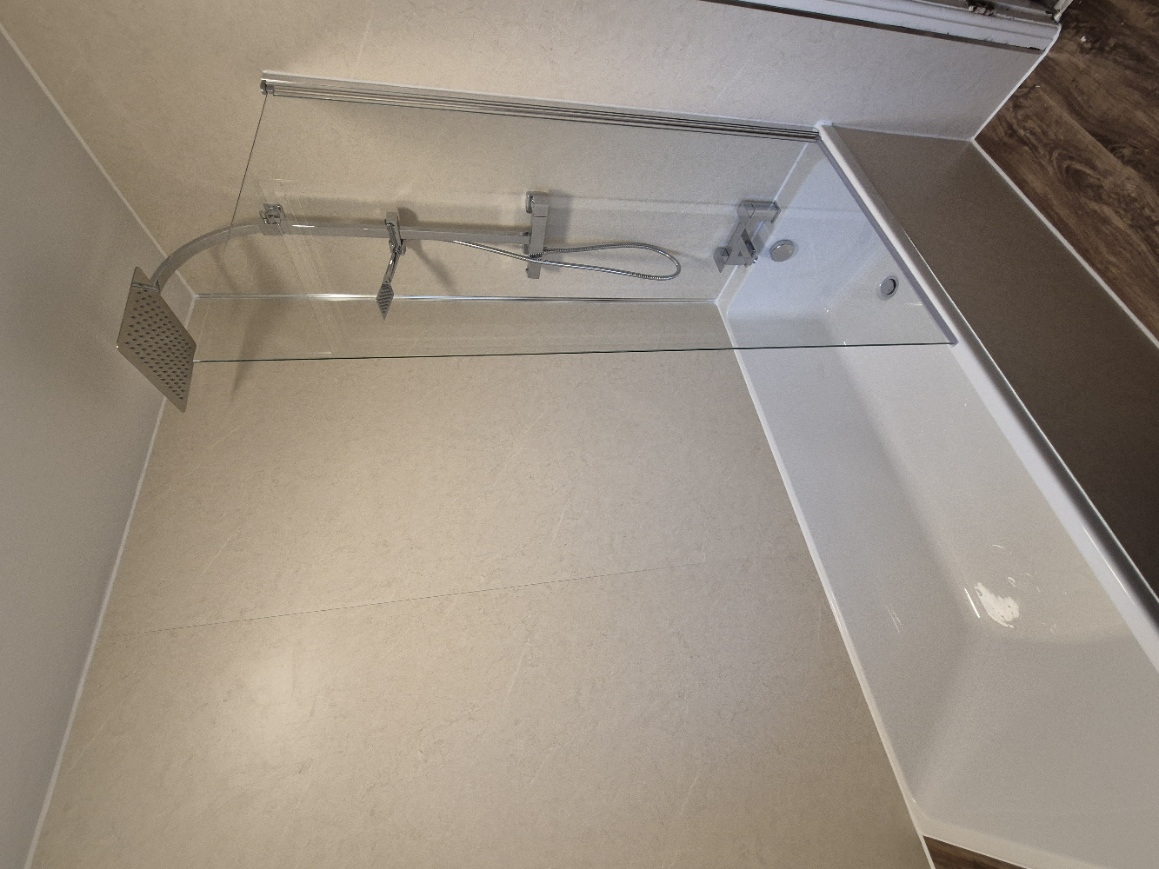Completed bath and rainfall shower installation with glass shower screen and wall panels