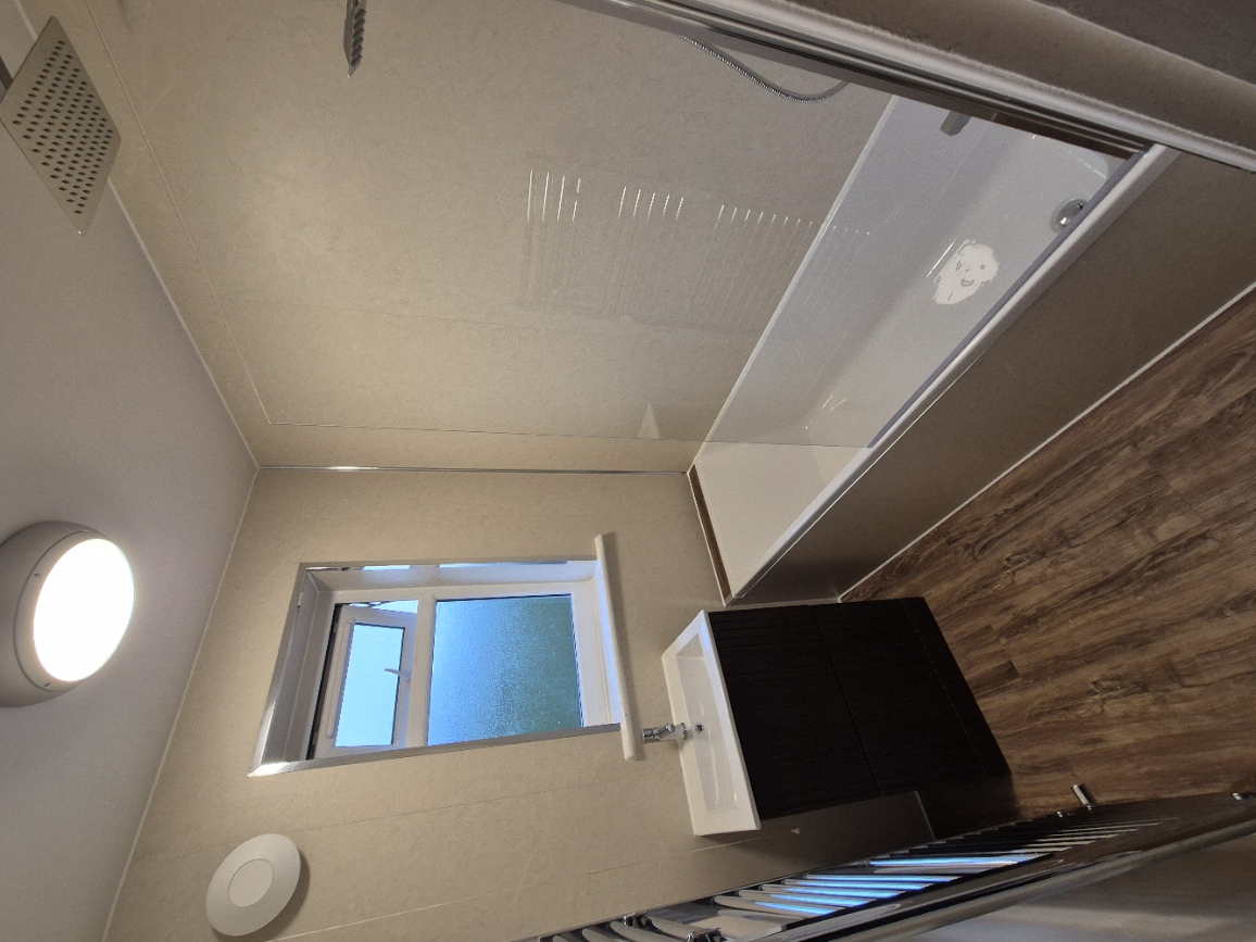 Finished bathroom with bath, shower screen, rainfall shower, vanity and towel radiator