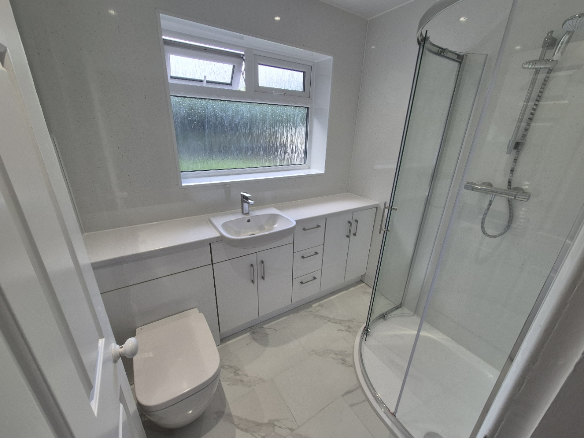 Completed shower room with fitted vanity, WC, curved shower enclosure and finished flooring